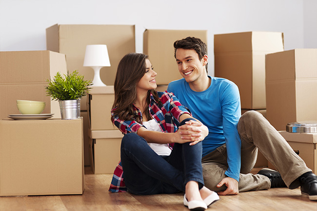 A couple sitting down on a floor in their new home